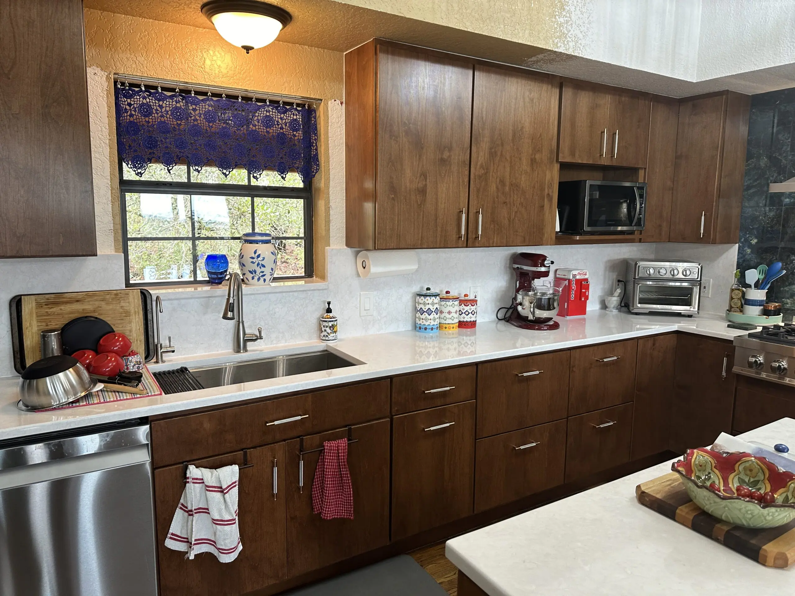 Kitchen with brown plain cabinets white cambria brand quartz countertops. Bertch brand cabinets